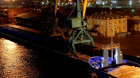 Empty long barge and ship on the dark water in the seaport with buildings under Видео 73824311