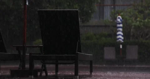 Empty lounge chair by pool under heavy rain, urban setting with Stock Footage 312002588