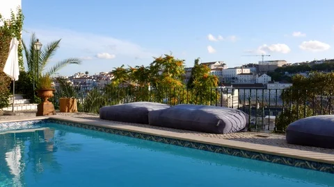 Empty luxurious swimming poolside area on sunny and breezy day overlooking Stock Footage 111020542
