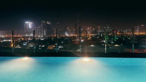 Empty luxury rooftop infinity pool with panoramic Dubai skyline view at night Stock Footage 328189557