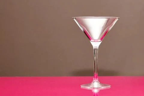 An empty martini glass stands on a bar counter. Background no focus. Close-up Stock Photos