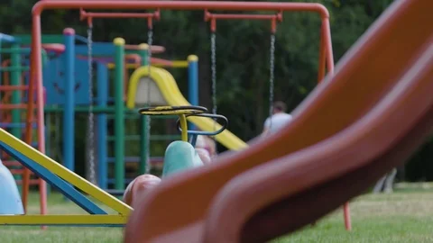 Empty merry-go-round spinning by itself in a children playground Stock Footage 99732859