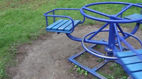 Empty merry-go-round spins on a playground, creating loneliness. Stock Footage 318543998