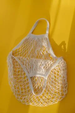 Empty mesh string bag on bright yellow background and hard sunshine. The concept Stock Photos