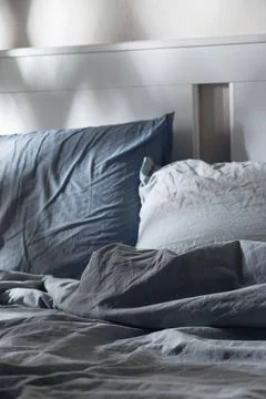 Empty messy bed with pillows in the moonlight. Darkness and evening rituals for Stock Photos