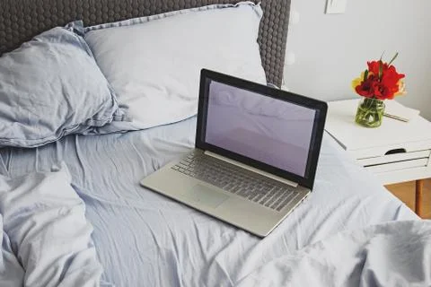 Empty messy grey bed with laptop in minimalist bedroom Stock Photos