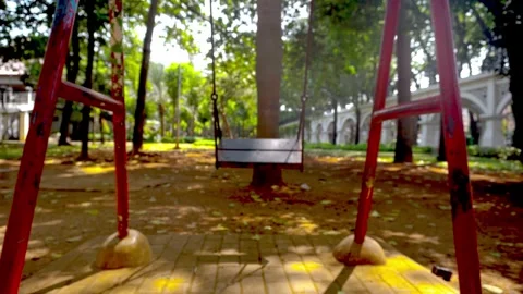 An empty metal playground swing moves gently on its own in a quiet public p.. Stock Footage 342024030