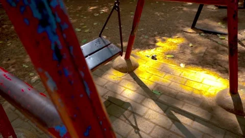 An empty metal playground swing moves gently on its own in a quiet public p.. Stock Footage 342024073