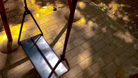 An empty metal playground swing moves gently on its own in a quiet public p.. Stock Footage 342024136