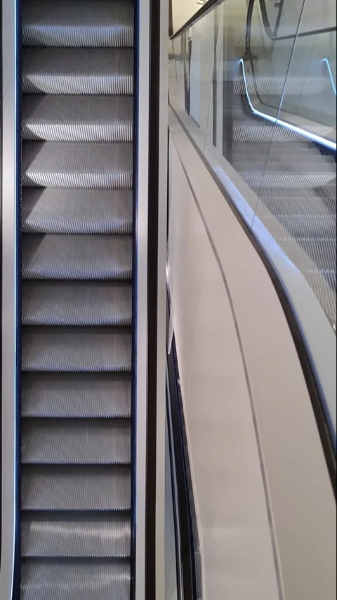 Empty metal steps of an escalator moving upwards inside a modern building, Vídeos de archivo 347030165