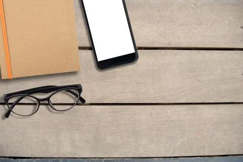Empty mobile screen and book of brown and eye glasses on desk, top view, copy Stock Photos