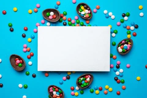 Empty mockup white blank on a blue Easter background. Multi-colored candy. .. Stock Photos