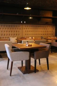 Empty modern café interior featuring a solid wooden dining table flanked Stock Photos