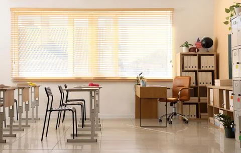 Empty modern classroom interior with student desks, teachers desk, and storag Stock Photos