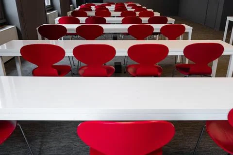Empty modern classroom with red seats and white tables Stock Photos