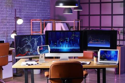Empty modern office desk with multiple computer monitors displaying financial Stock Photos