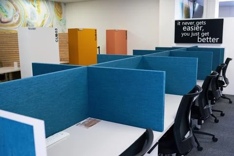 Empty modern office space with row of desks separated by desk dividers Stock Photos