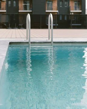 Empty modern swimming pool with clear blue water and metal ladder photograp.. Fotos Stock