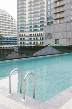 Empty modern swimming pool with clear blue water and metal ladder photograp.. Fotos Stock
