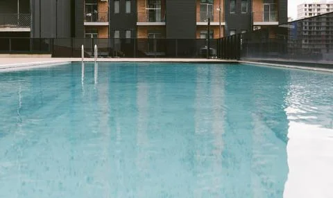 Empty modern swimming pool with clear blue water and metal ladder photograp.. Stock Photos