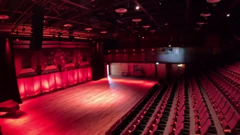 Empty modern theater hall with dramatic red stage lighting and rows of seats Stock Footage 340084983