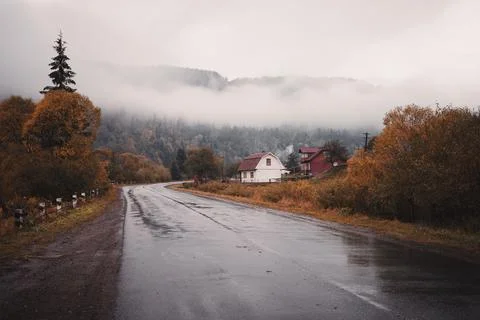 Empty mountain road during autumn rain and village houses Stock Photos