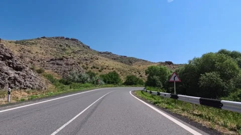 Empty mountain road with guardrails, trees, and rocky hillsides under brigh.. Stock Footage 340077830
