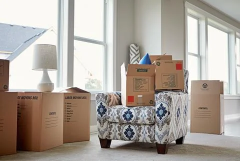 Empty, moving and boxes on sofa in home for relocation, property investment.. Stock Photos