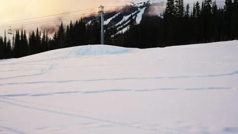 Empty moving cableway lift chairs on the snowy ground and trees at sunset Stock-Footage 145555459