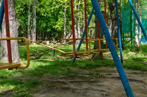 Empty multi-colored swing in the park on a summer day Stock Photos