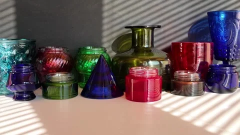 Empty multi-colored various glass wares are on a table  in sun rays Stock Footage 303929367