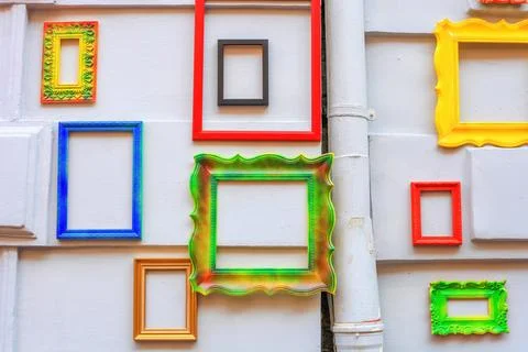 Empty multicolor photo frames hang on white wall of an old house Foto stock