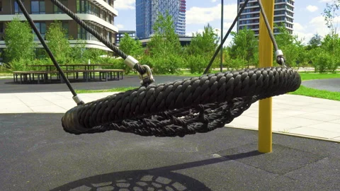 Empty nest web swing swinging outdoors on modern playground on sunny day Stock Footage 340579818