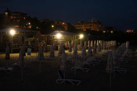 Empty night beach with empty sunbeds and umbrellas Stock Photos
