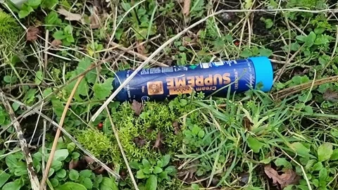 Empty nitrous oxide metal bottle discarded drug container on public park grass Stock Footage 329478115