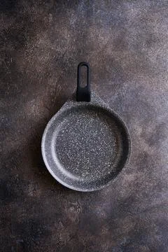 Empty nonstick serving pan on dark textured background, close-up, top view Stock Photos