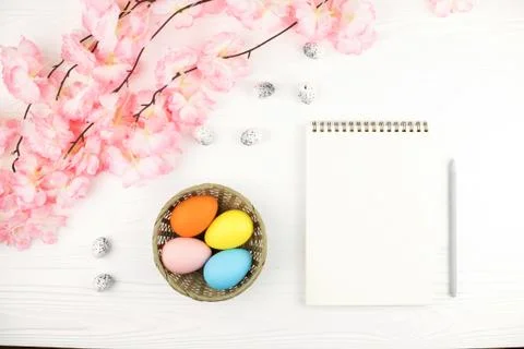 Empty notebook and basket with eggs on Easter background. Stock Photos