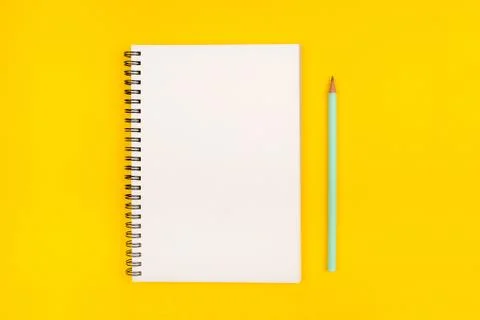 Empty notebook and pencil on yellow background, top view. Stock Photos