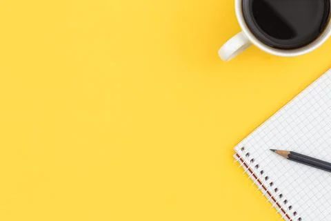Empty notebook with cup of coffee on a yellow background, flat lay. Stock Photos