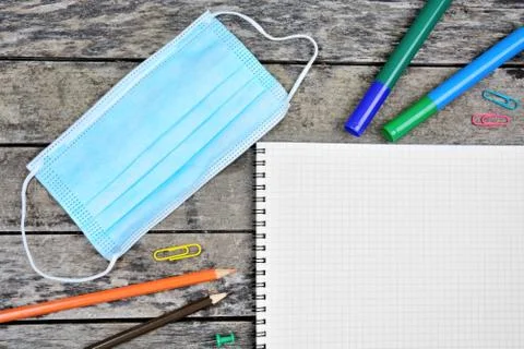 Empty notebook with face mask, colorful markers and pencils Stock Photos