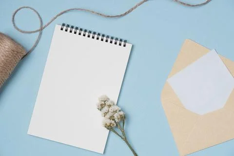 Empty notebook with flower, string, letter on blue background from above. Cop Stock Photos