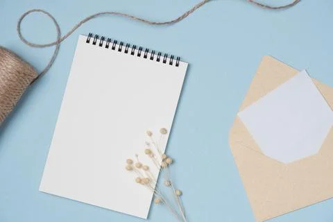 Empty notebook with flower, string, letter on blue background from above. Cop Stock Photos