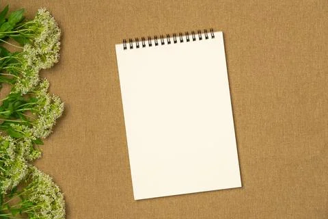 Empty notebook with flowers on fabric background. Flat lay, top view. Space.. Stock Photos