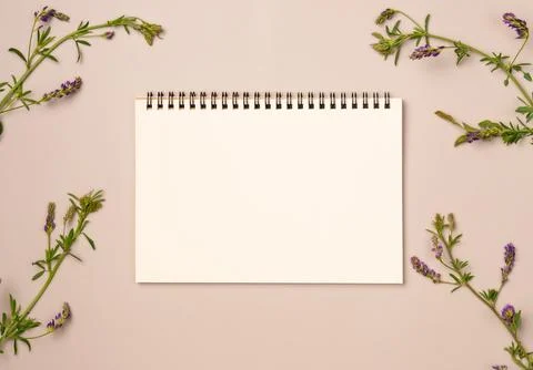 Empty notebook with flowers frame on beige background. Flat lay, top view. .. Stock Photos