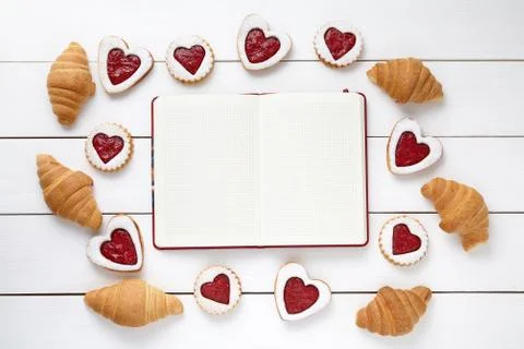 Empty notebook frame for design text, croissants and heart shaped cookies Stock Photos