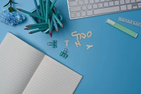 Empty notebook, keyboard and pencil holder on blue background. Foto stock