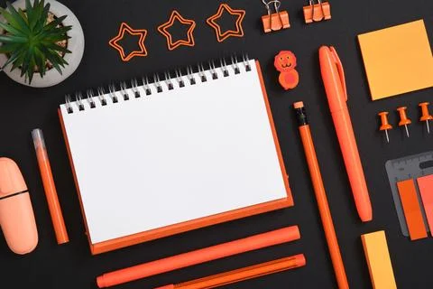 Empty notebook page for text in frame of orange stationery set on black back Stock Photos