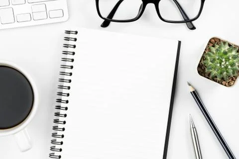 Empty notebook page is on top of white office desk table with supplies. Top v Stock Photos