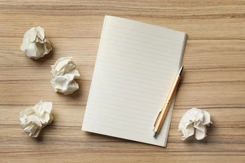 Empty notebook with pen and crumpled paper balls on wooden table, flat lay. S Stockfoto's
