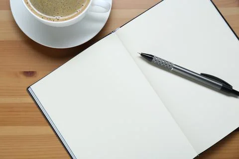 Empty notebook, pen and cup of coffee on wooden table, flat lay Stock Photos